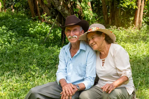 Pareja matrimonial anciana sonriendo sentada junta en el campo